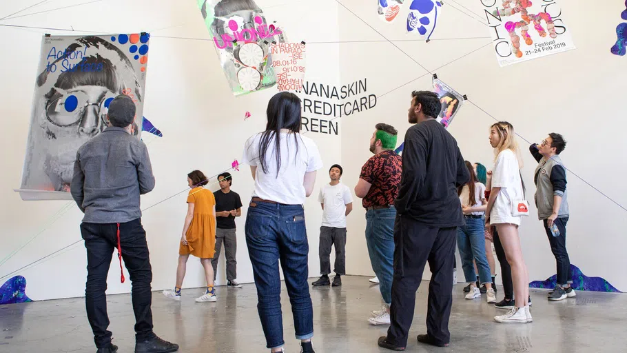 A class looks at an installation of posters and vinyl in the Nave Alcove.