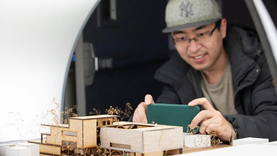 A close-up of a student documenting a laser cut model in an Orbiculight.