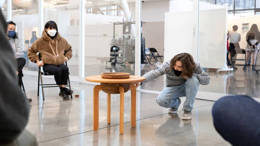 A Furniture student presents a conical sculpture to a small panel in the Nave.