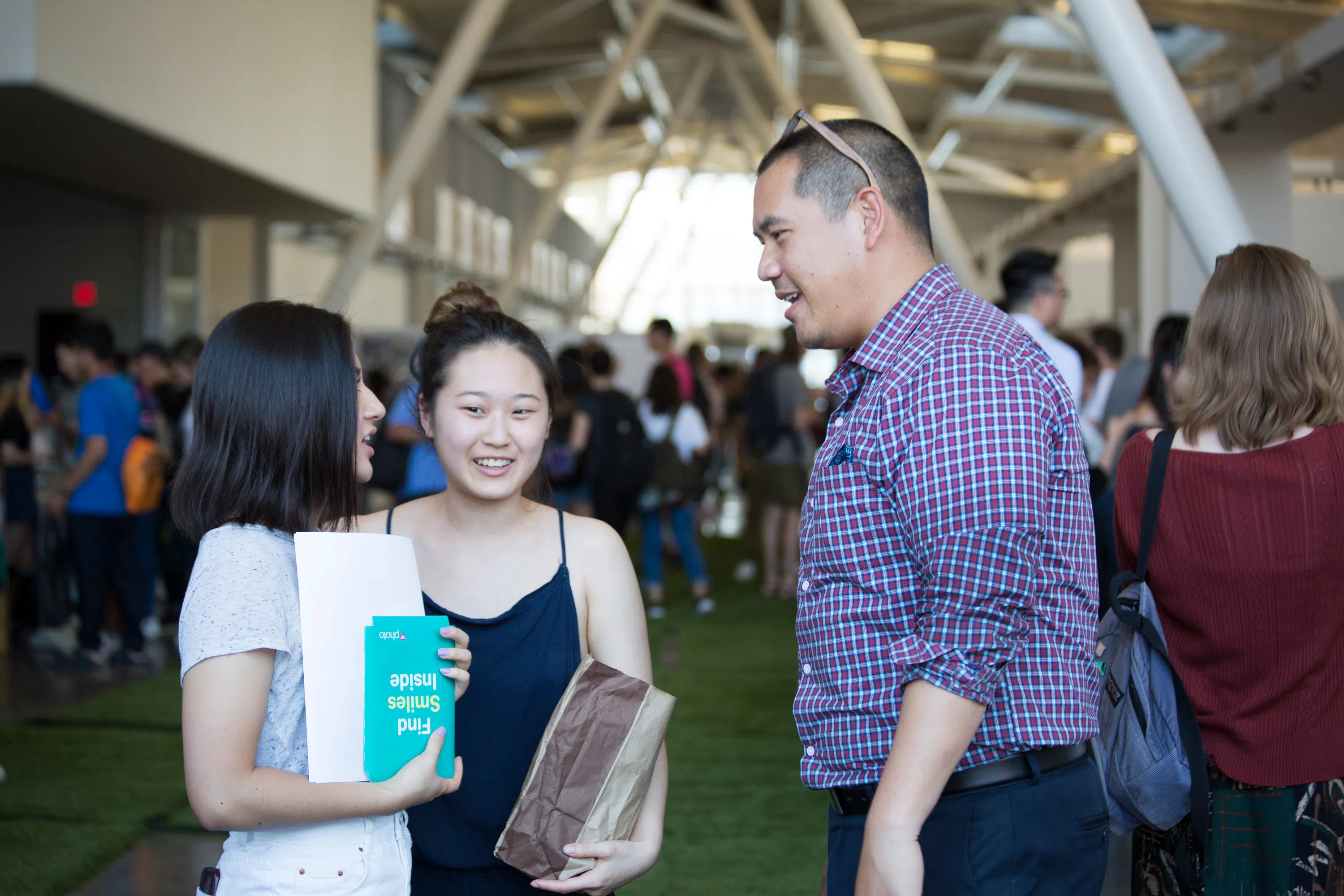 Two students talk with Noki Seekao with the crowded Nave behind them.