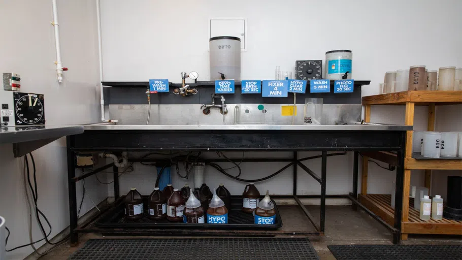 A large metal sink with signs and containers. 