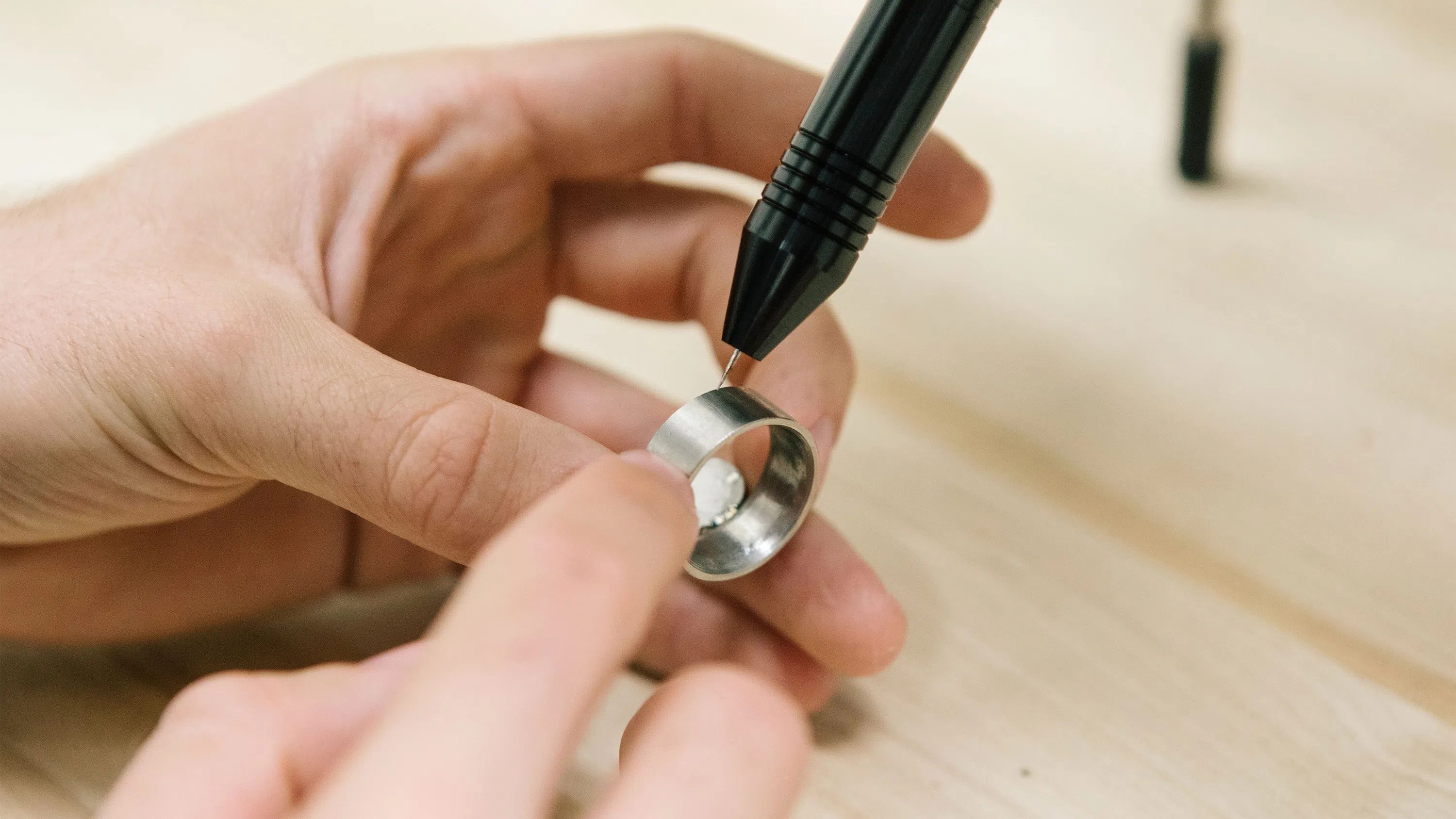 A close-up of a student engraving a metal ring with an engraver.