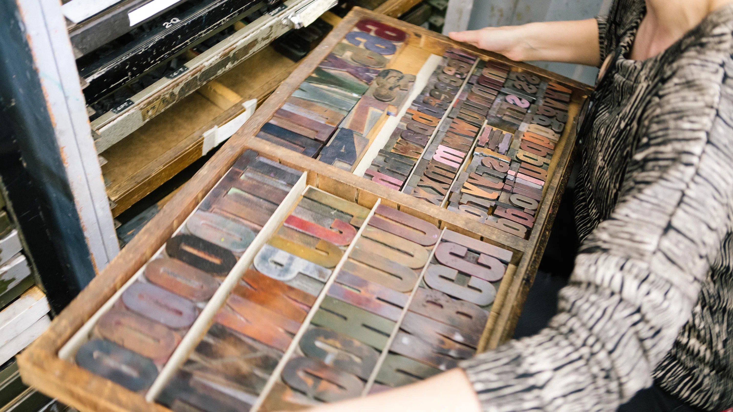 Assistant Professor Anthea Black holds a typesetting tray with letterpress print type.