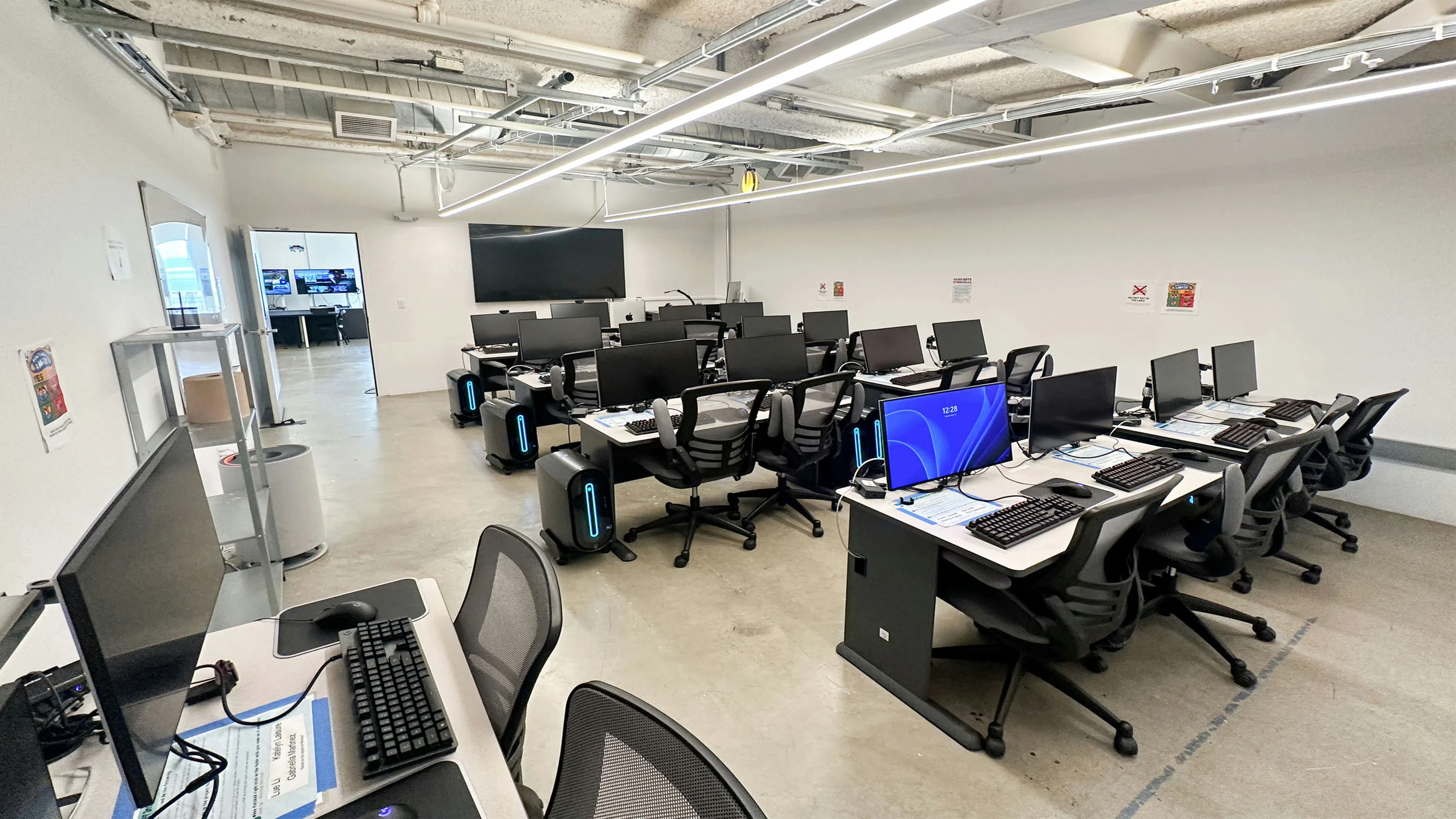 A computer lab with several rows of computers and desks. 