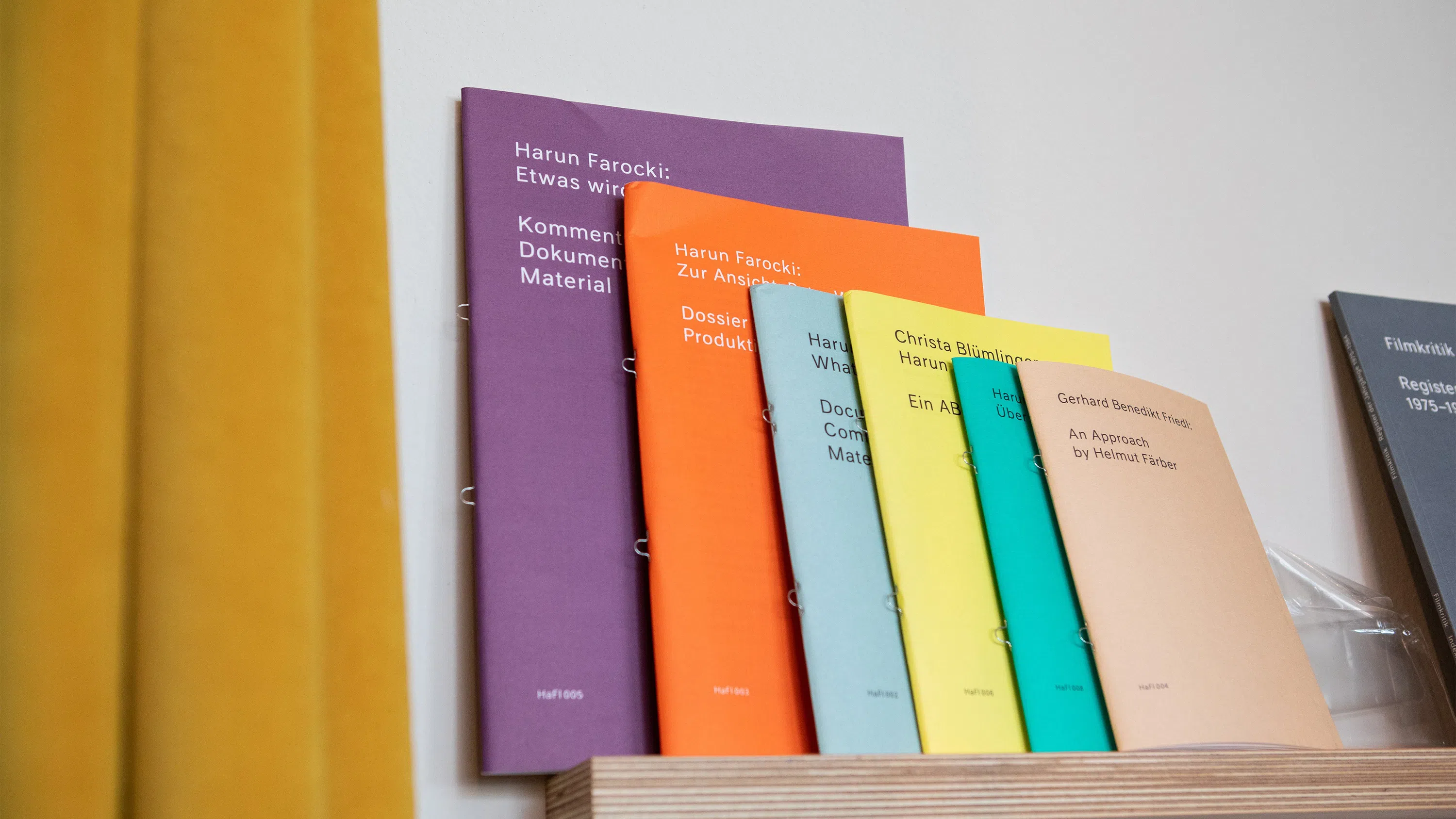 A group of six, colorful books arranged by size on a wooden shelf.