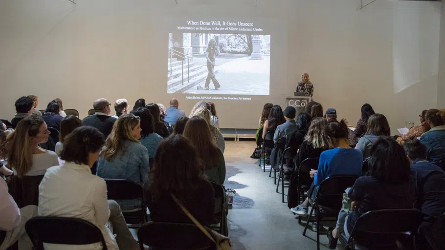 A speaker stands at a podium in front of a room full of people.