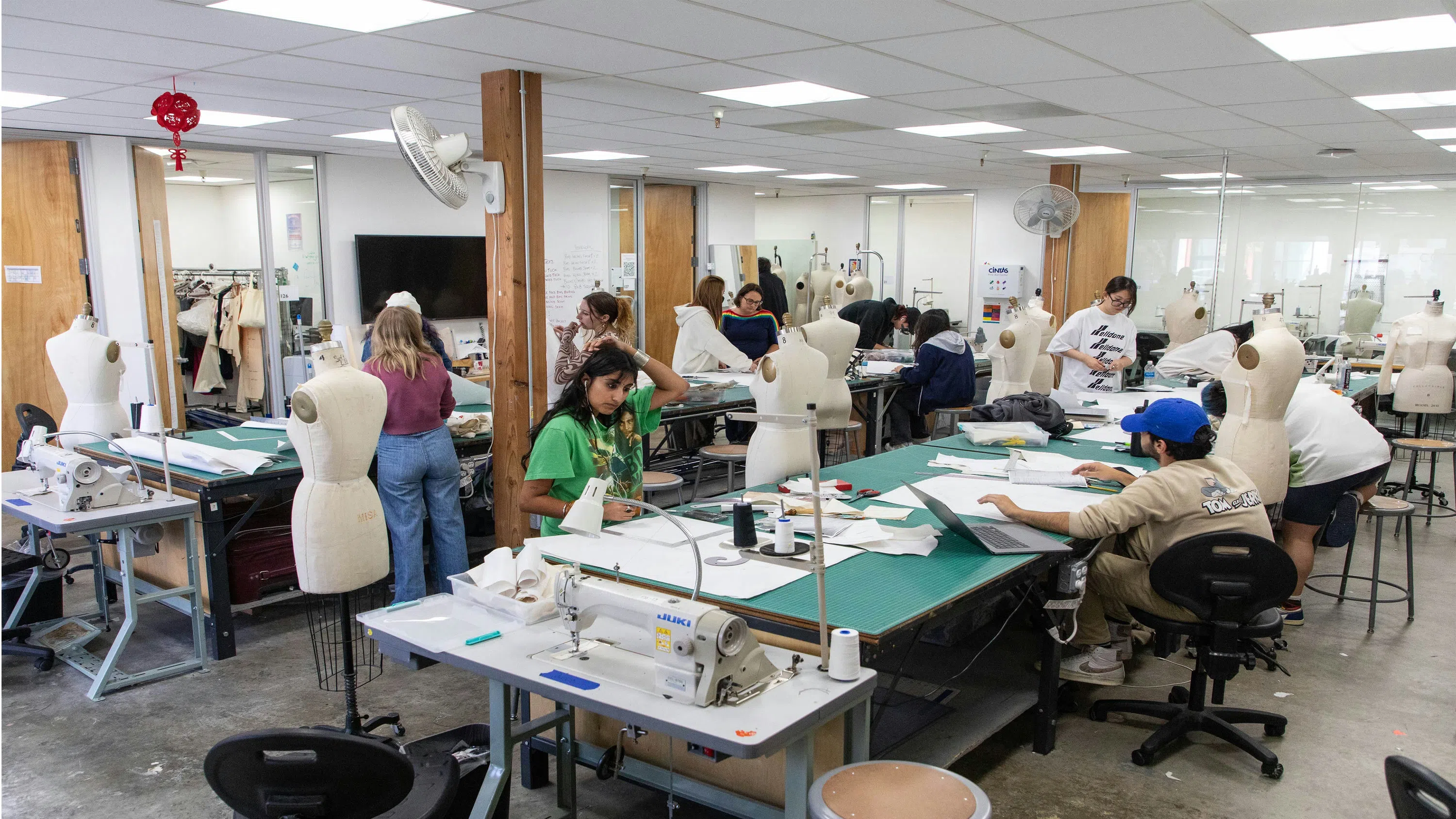 A group of individuals collaborating in a sewing room, stitching fabrics and bringing designs to life.