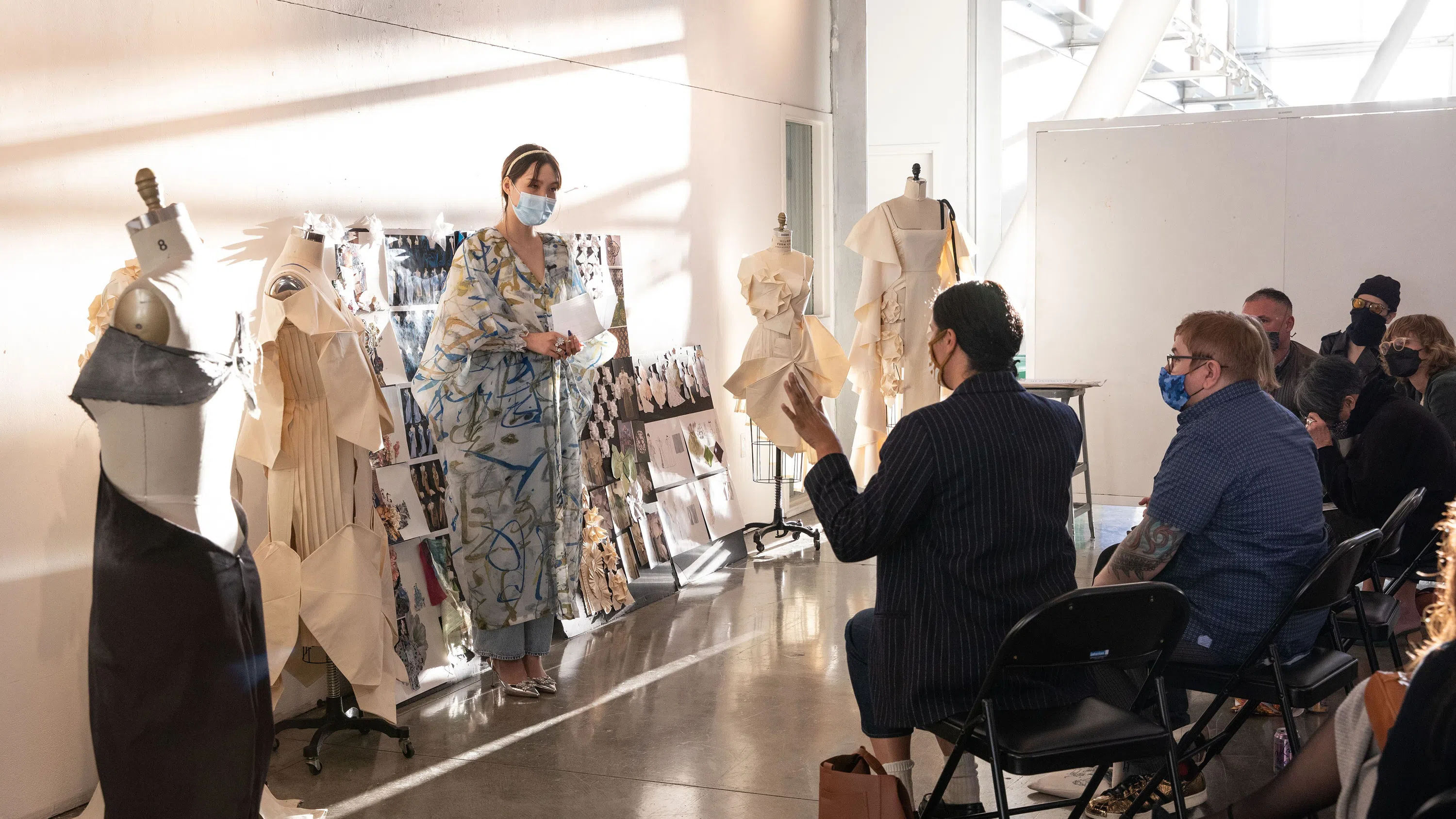A Fashion Design student presents her designs to a panel during critique in the Nave.