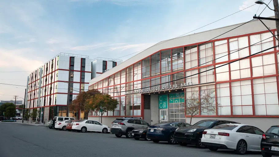 Pedestrian view of the Main Building with cars lined up in front.