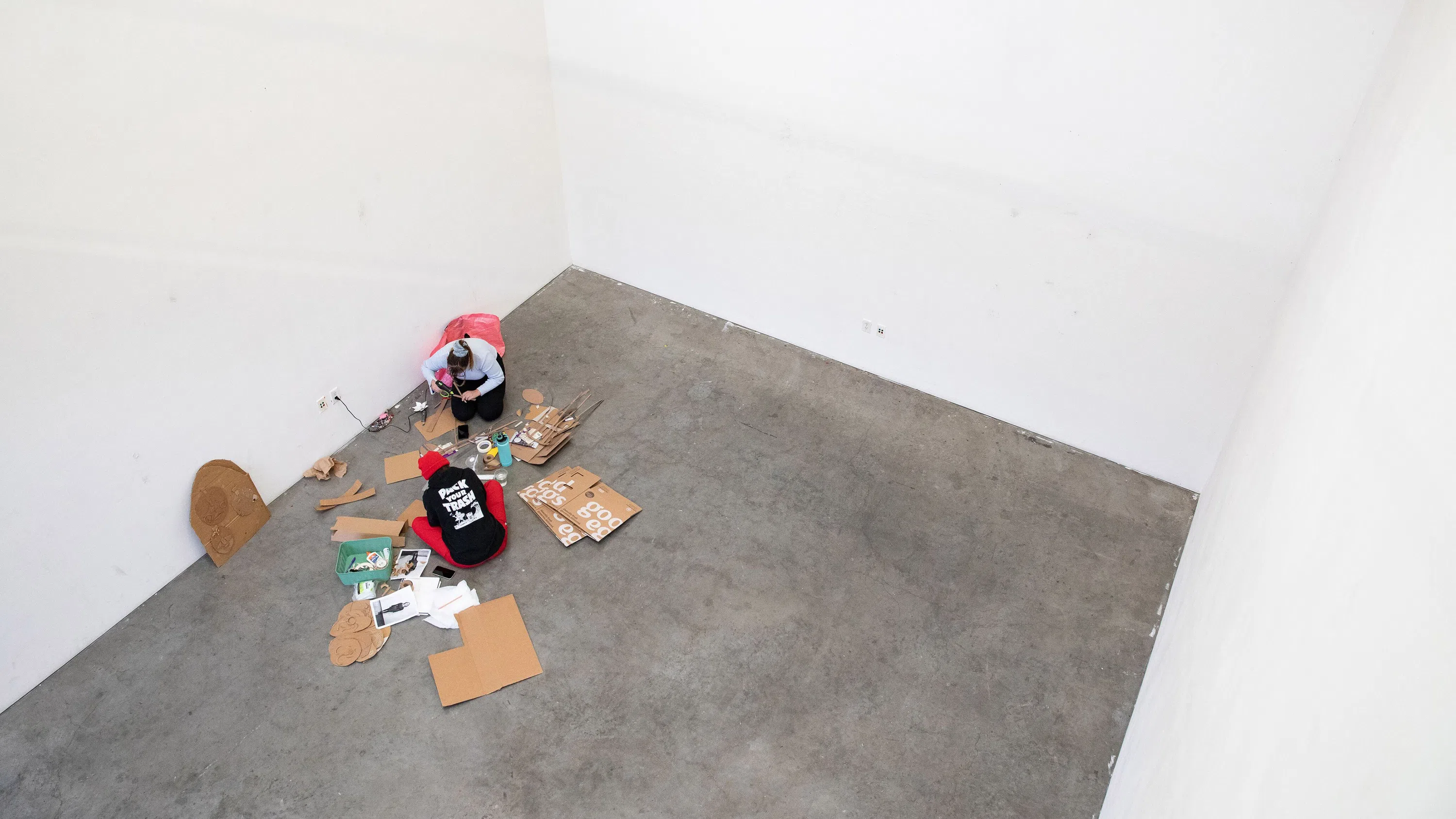 An overhead view of two students working on their Protest Prosthetics project in a white presentation space.