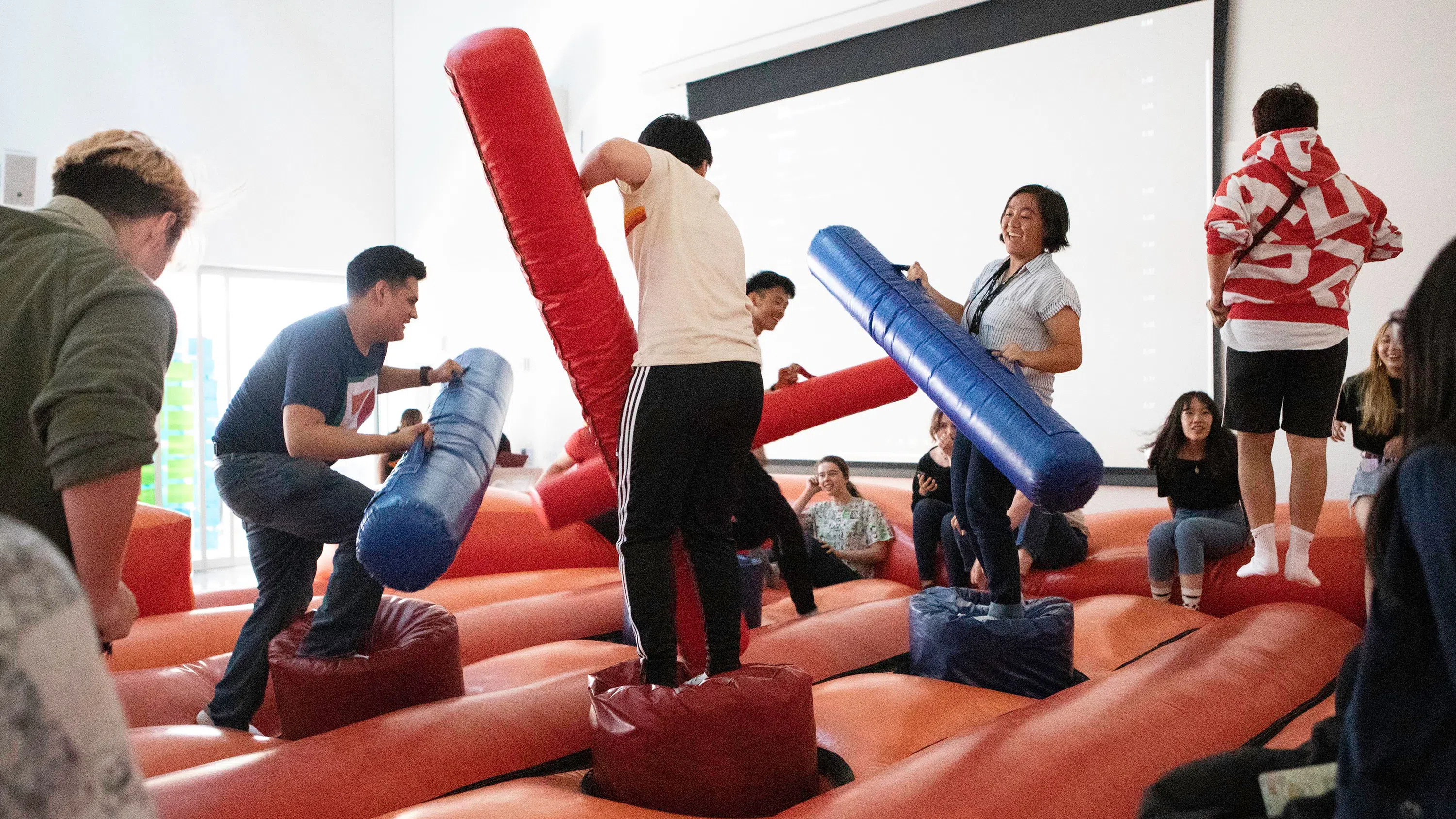 Students play with large inflatable objects in a bouncy-house environment in the Nave.