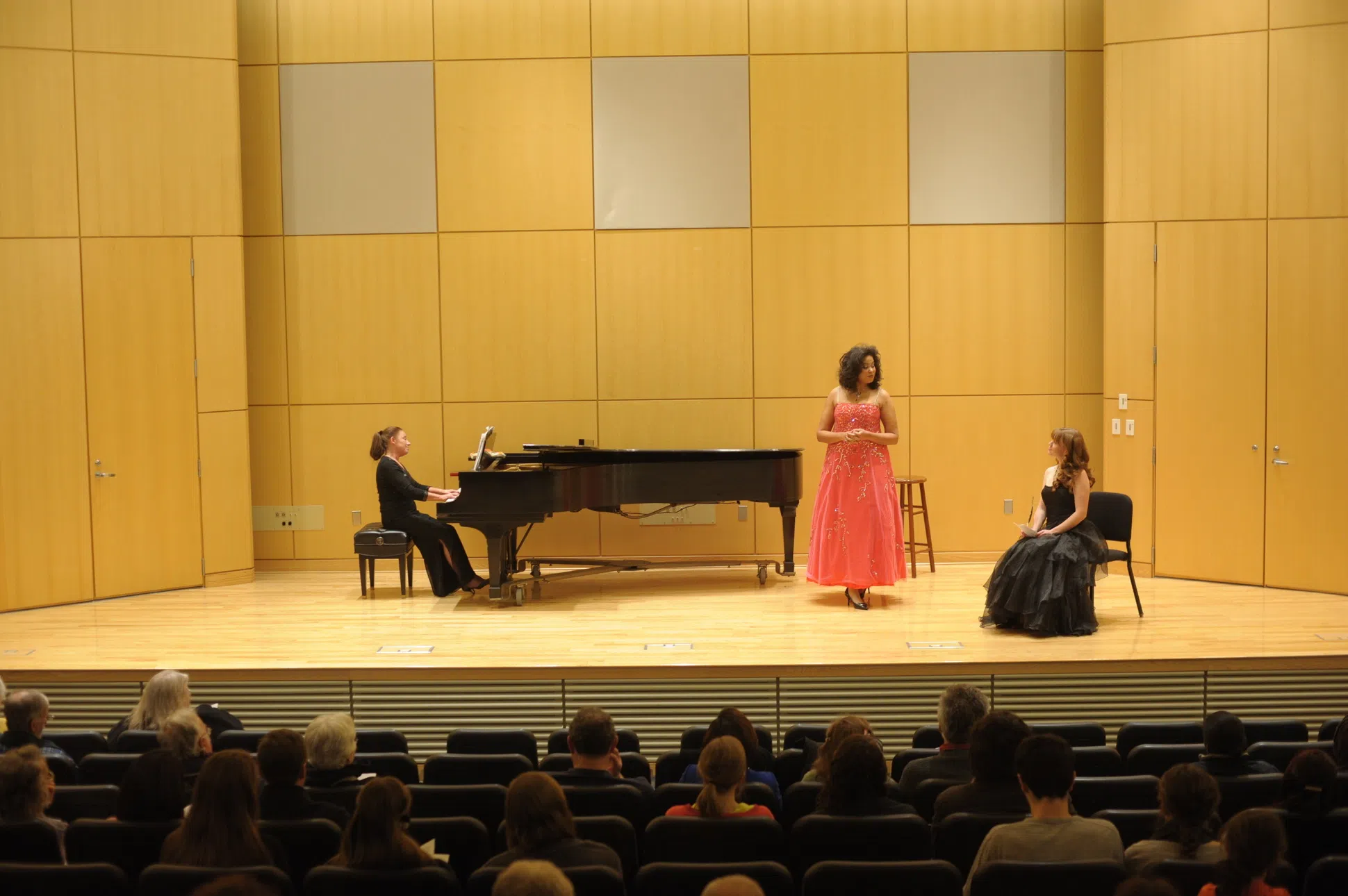 concert hall with stage, piano, and three performers
