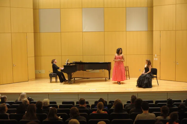 concert hall with stage, piano, and three performers