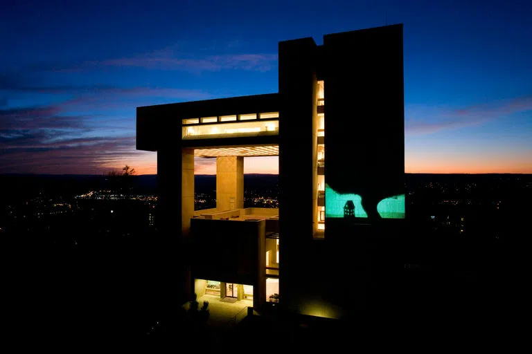 The Johnson Museum of Art lit up at dusk with a projection on the outside wall.