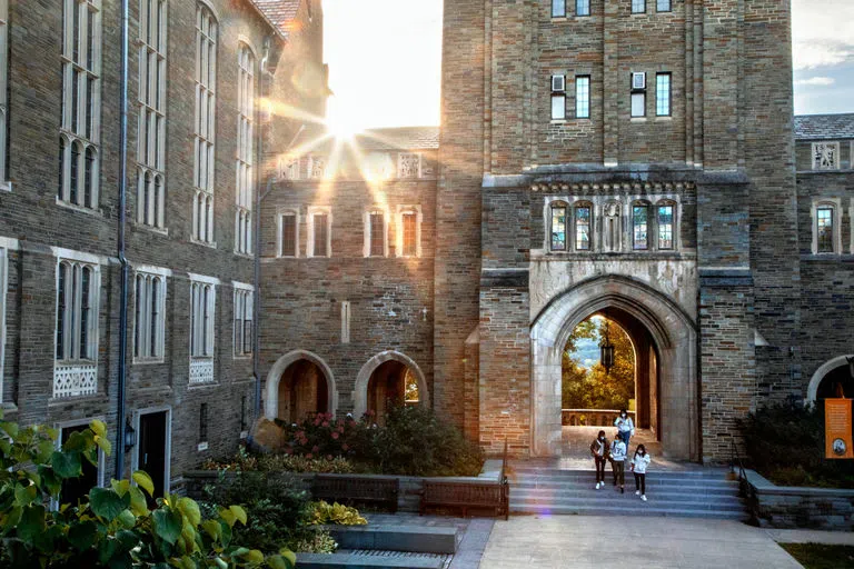 Students walk outside of Myron Taylor Hall in the early evening.