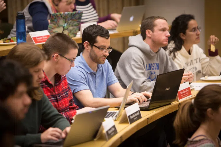 A row of graduate students with laptops, in a classroom.