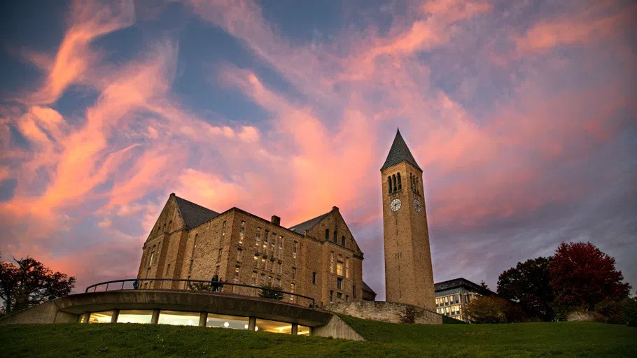 A dramatic sunset bathes Uris Library (left) and McGraw Tower (right) in streaks of purple and blue light. 