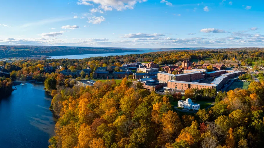 An aerial photo of the buildings on North Campus, Beebe Lake on the lower left and Cayuga Lake in the background on a colorful fall day.