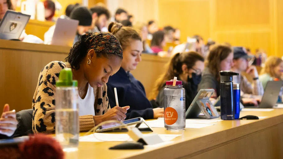 College of Veterinary Medicine students sit with their laptops and tablets, taking notes at long tables in stadium-style seating, for a lecture in CVM Center.