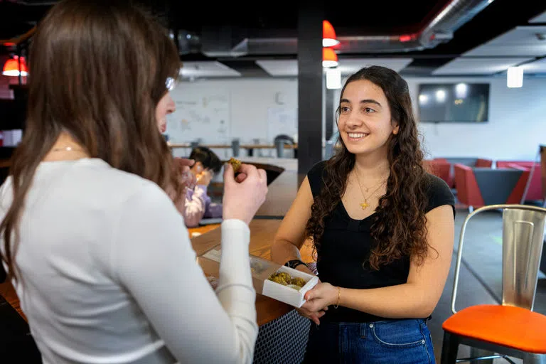 Student entrepreneur Armita Jamshidi ’25 shares a taste of her product, Cramp Bites, that she sells through her company, Aunt Flo’s Kitchen.