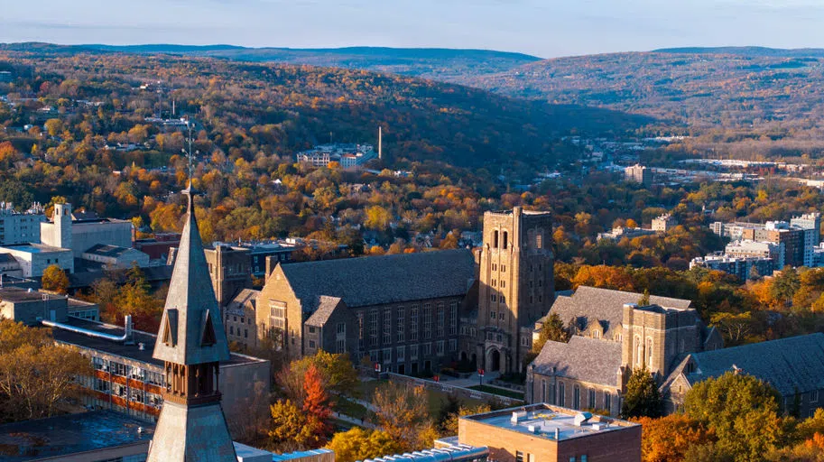 A colorful aerial view of Myron Taylor Hall on campus and the surrounding fall foliage in Ithaca.