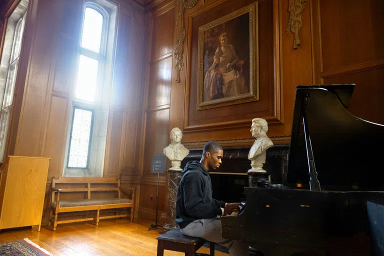 A student plays piano in Anabel Taylor Hall.