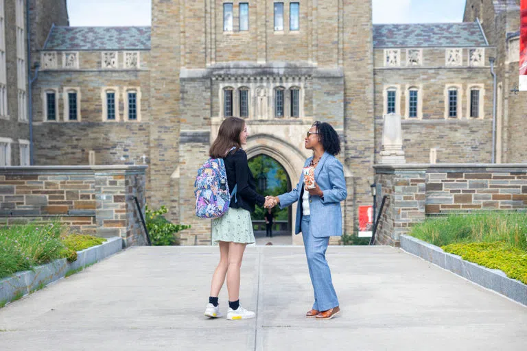 Two people greet each other outside Myron Taylor Hall.