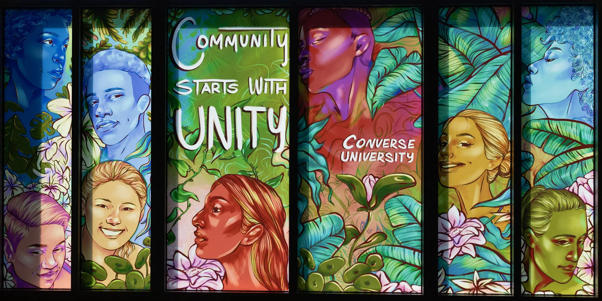 A six-paneled, painted window features a variety of diverse, multi-colored faces and the words: "Community Starts With Unity", as well as "Converse University".
