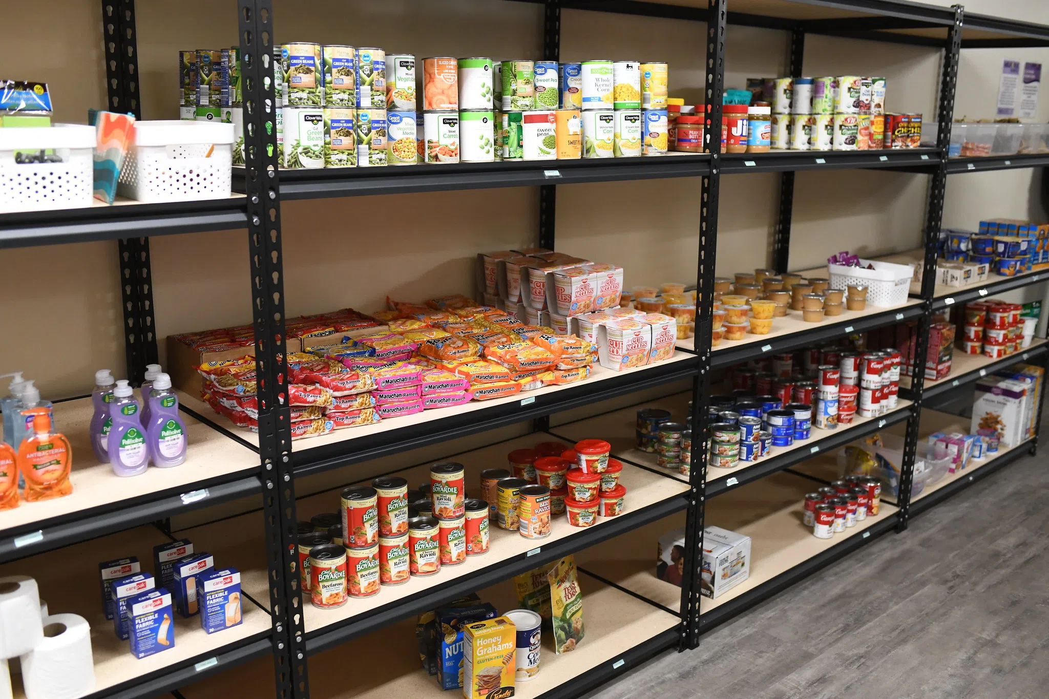 Shelves filled with canned goods and non-perishable food items line a wall.
