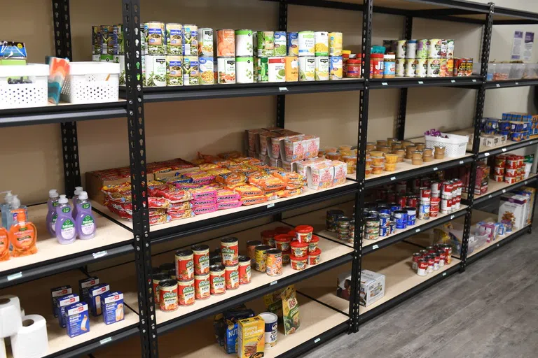 Shelves filled with canned goods and non-perishable food items line a wall.