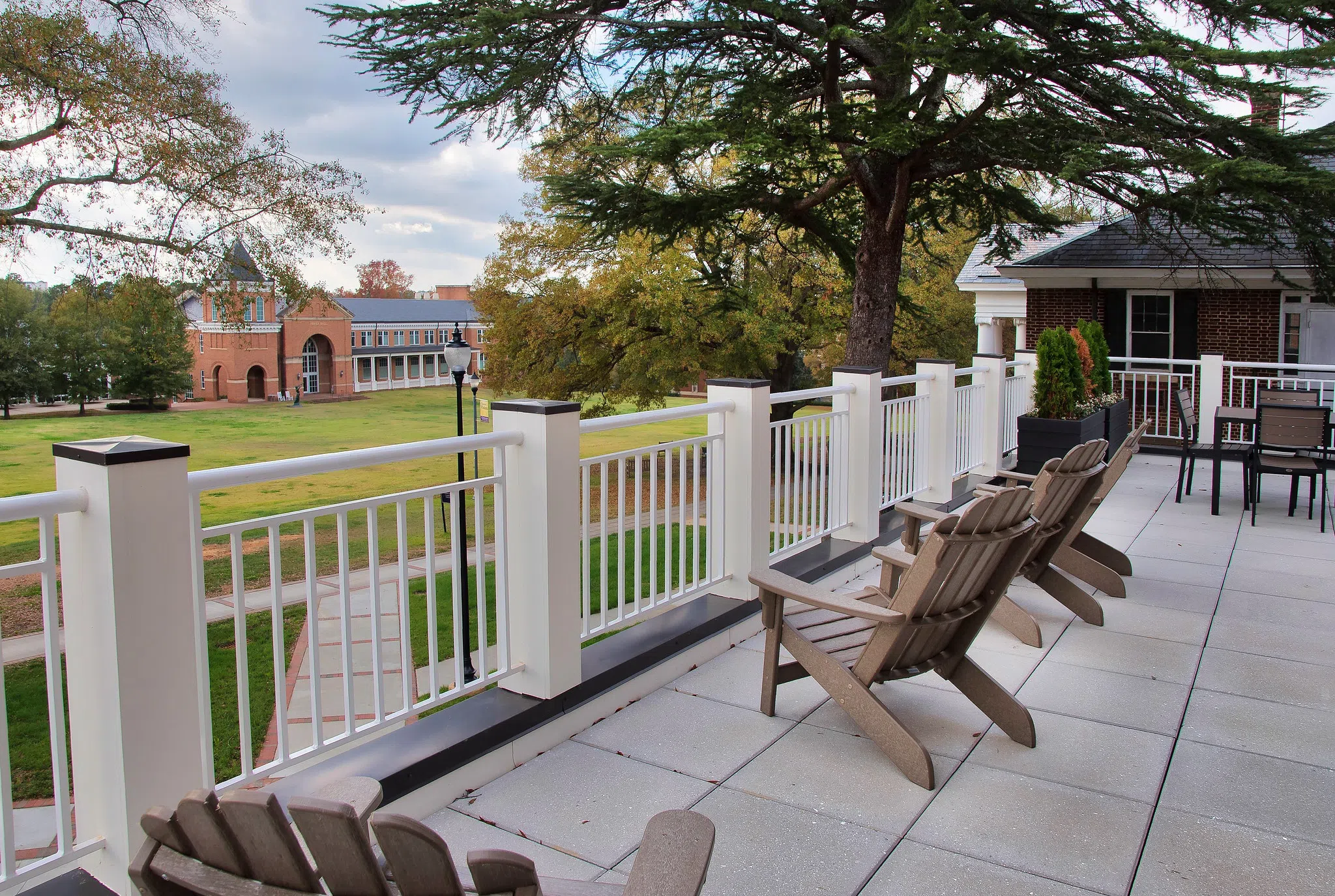 Adirondack chairs on an open patio overlook the large, grassy quad.