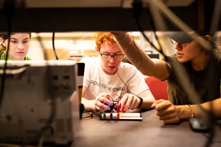 Three students working on an electrical component