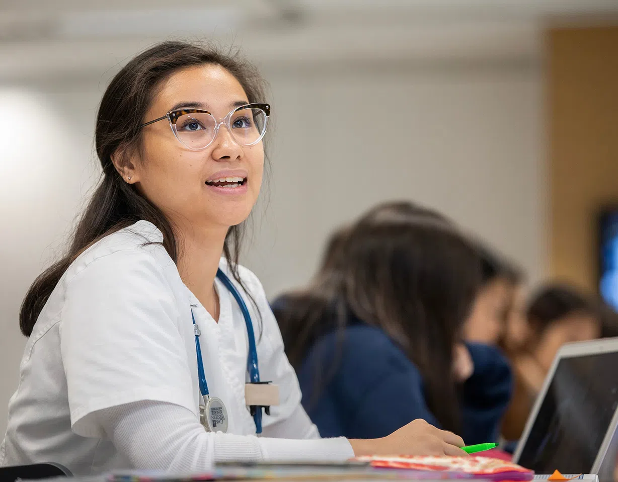 Nursing student wearing scrubs and working at a computer