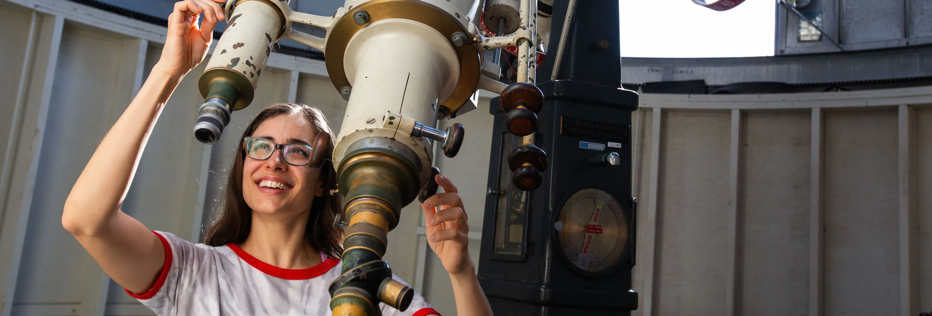 Student standing next to a large telescope