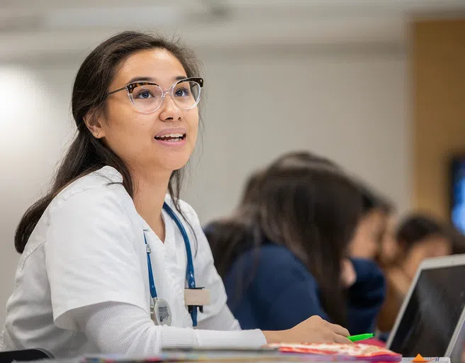 Nursing student wearing scrubs and working at a computer