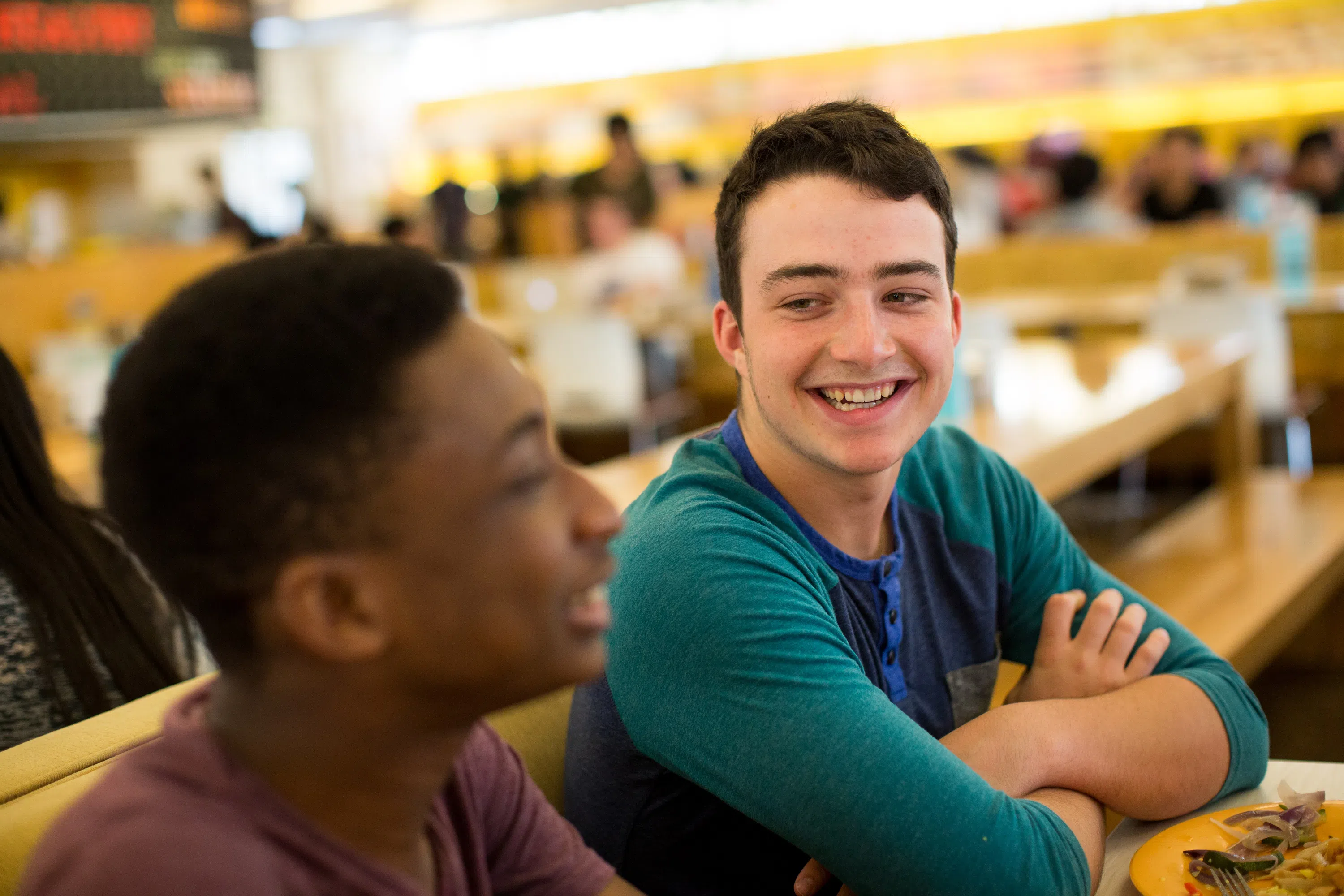 Two students talk and laugh at the dining hall