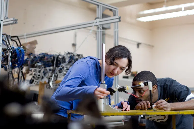 Two student engineers work with machinery