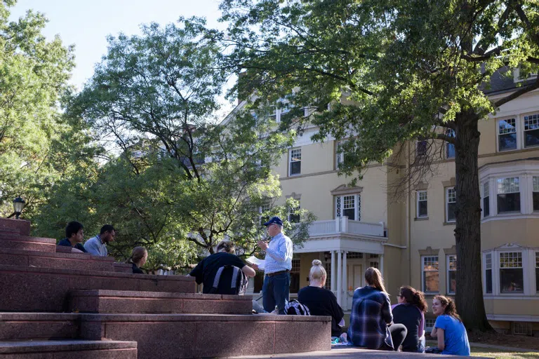 Faculty and students having class on the steps of the Merging sculpture