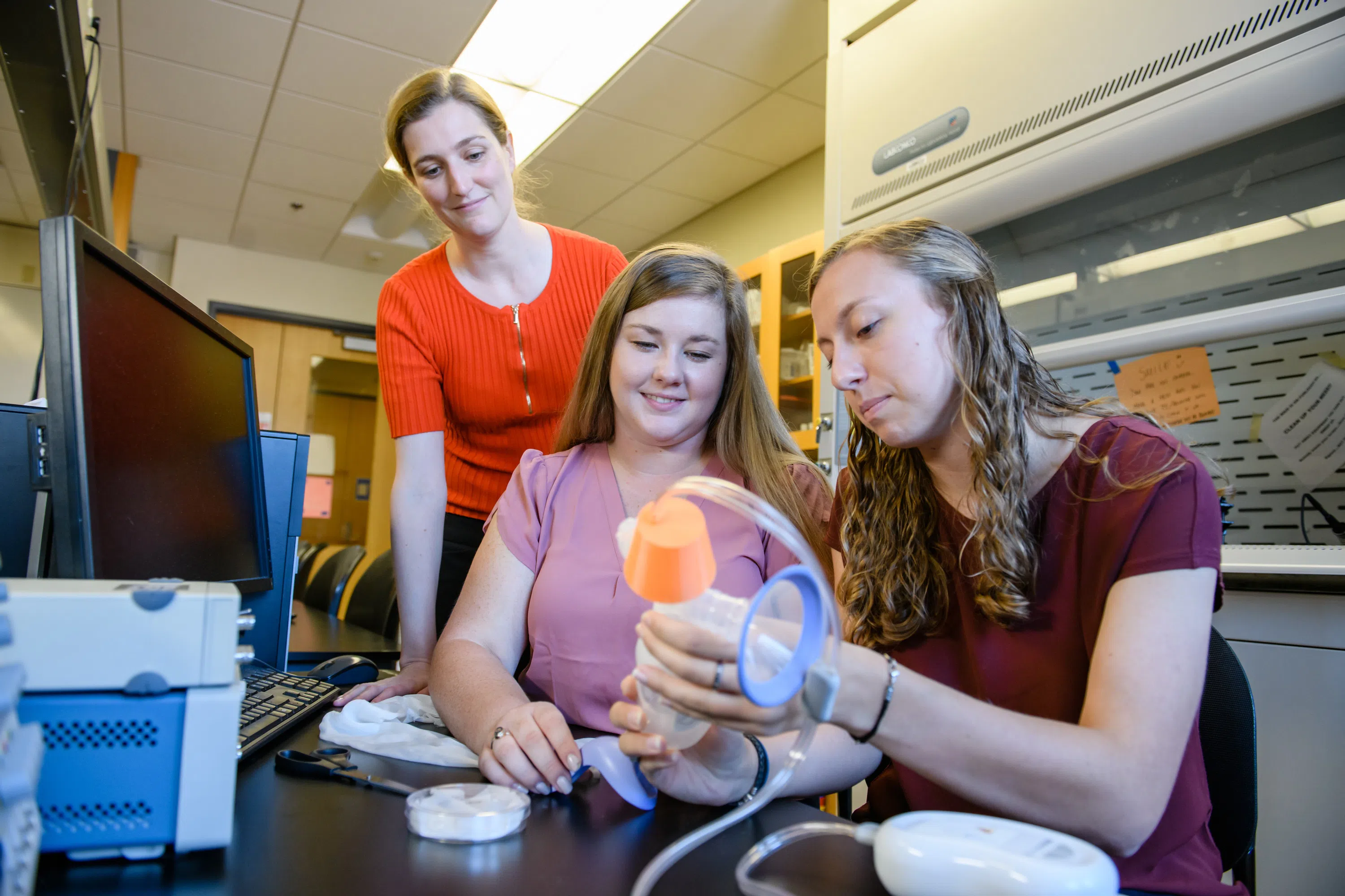 Bioengineering professor Delphine Dean works on a biomedical device with two students.