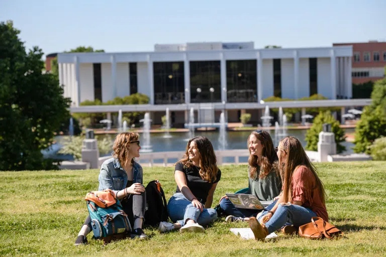 A group of female students sits on the North Green.