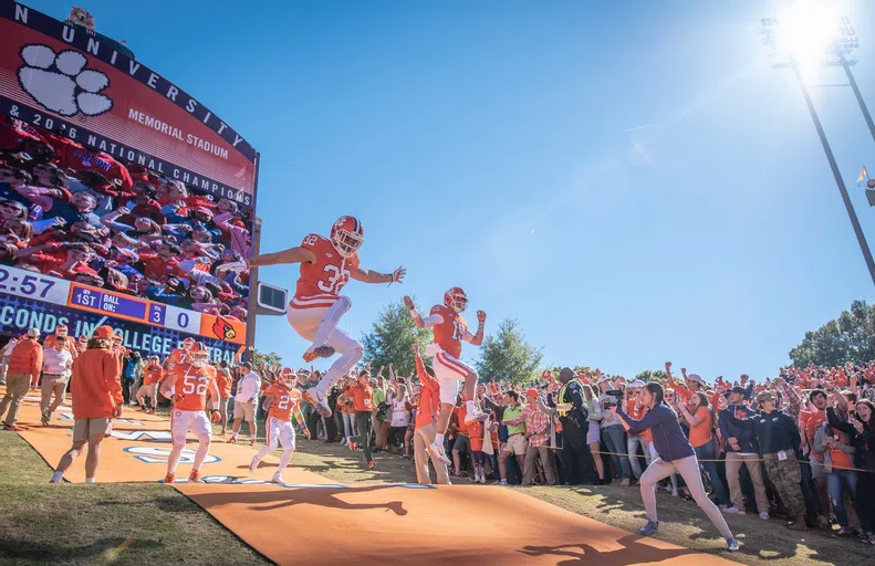 The Clemson Tigers football team runs down the hill into Death Valley to a crowd of screaming fans.