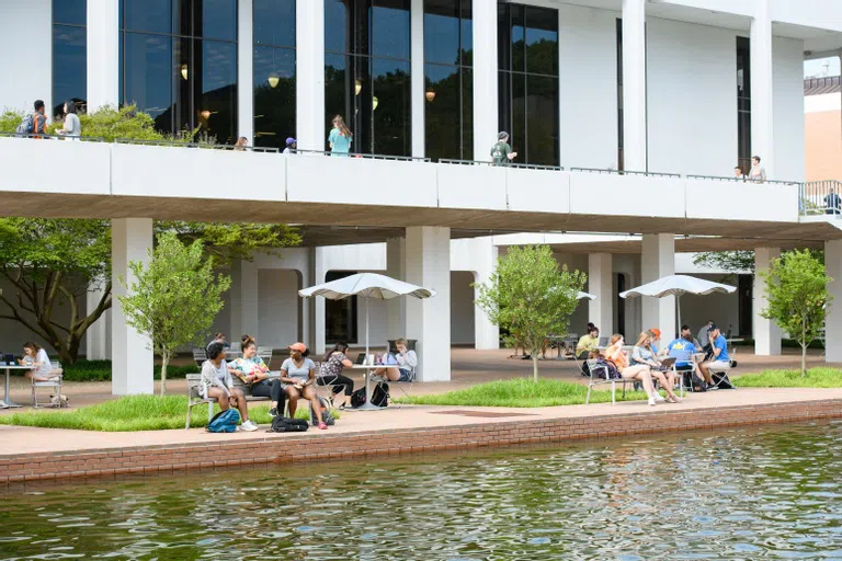 Various students sit outside the Library near the Reflection Pond.