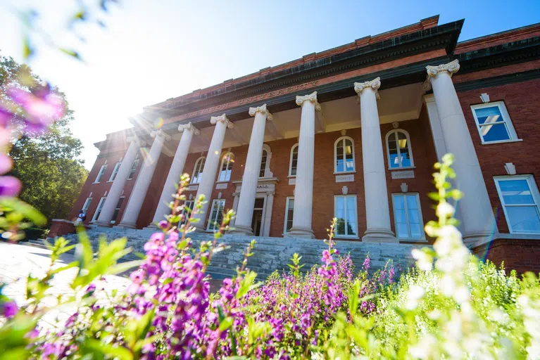 Sikes Hall on a spring day surrounded by pink and green flowers.