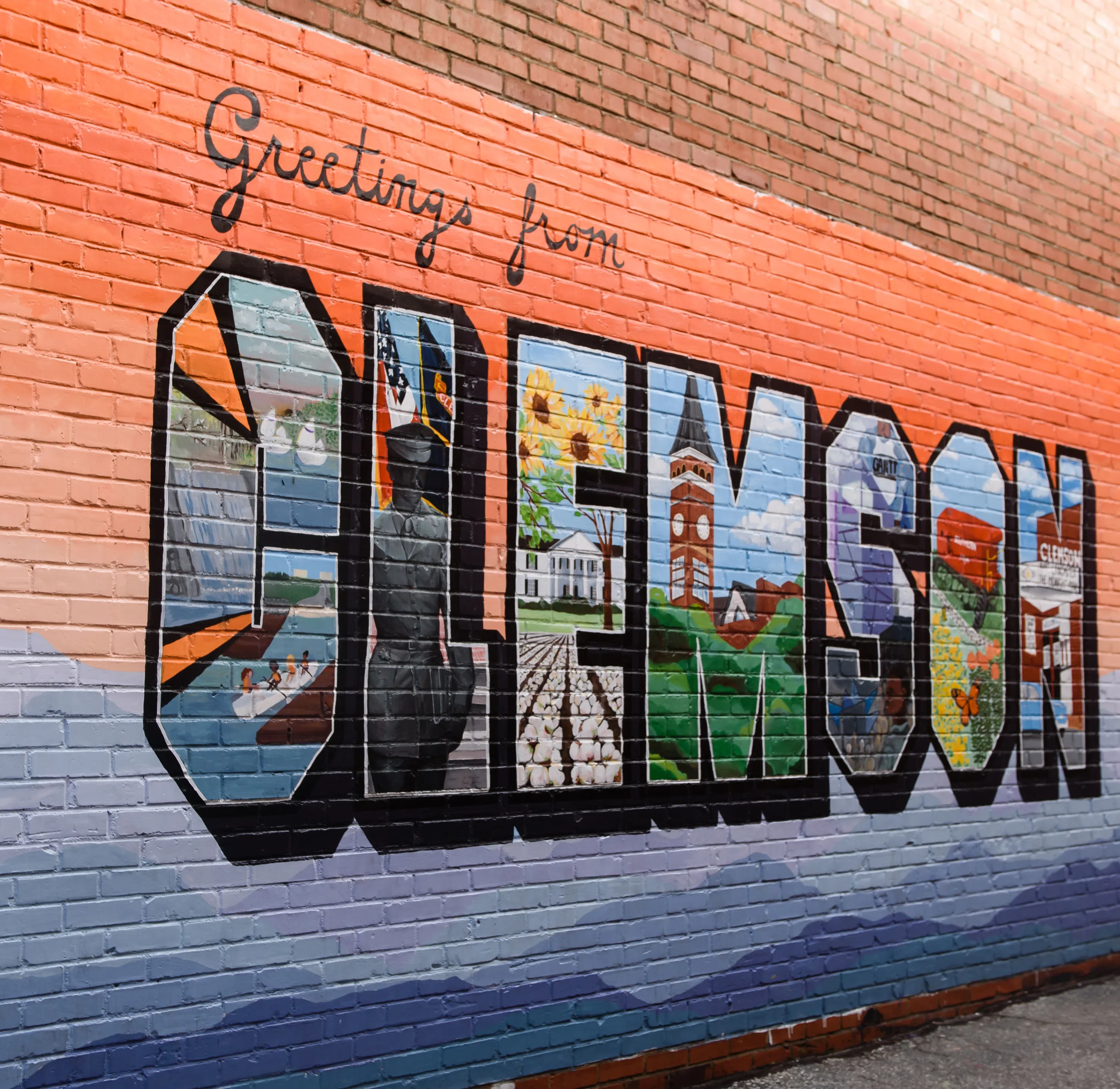 A mural on a brick wall in downtown Clemson that reads "Greetings from CLEMSON."