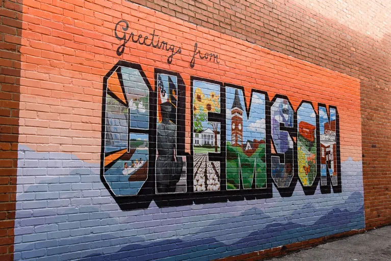 A mural on a brick wall in downtown Clemson that reads Greetings from Clemson.