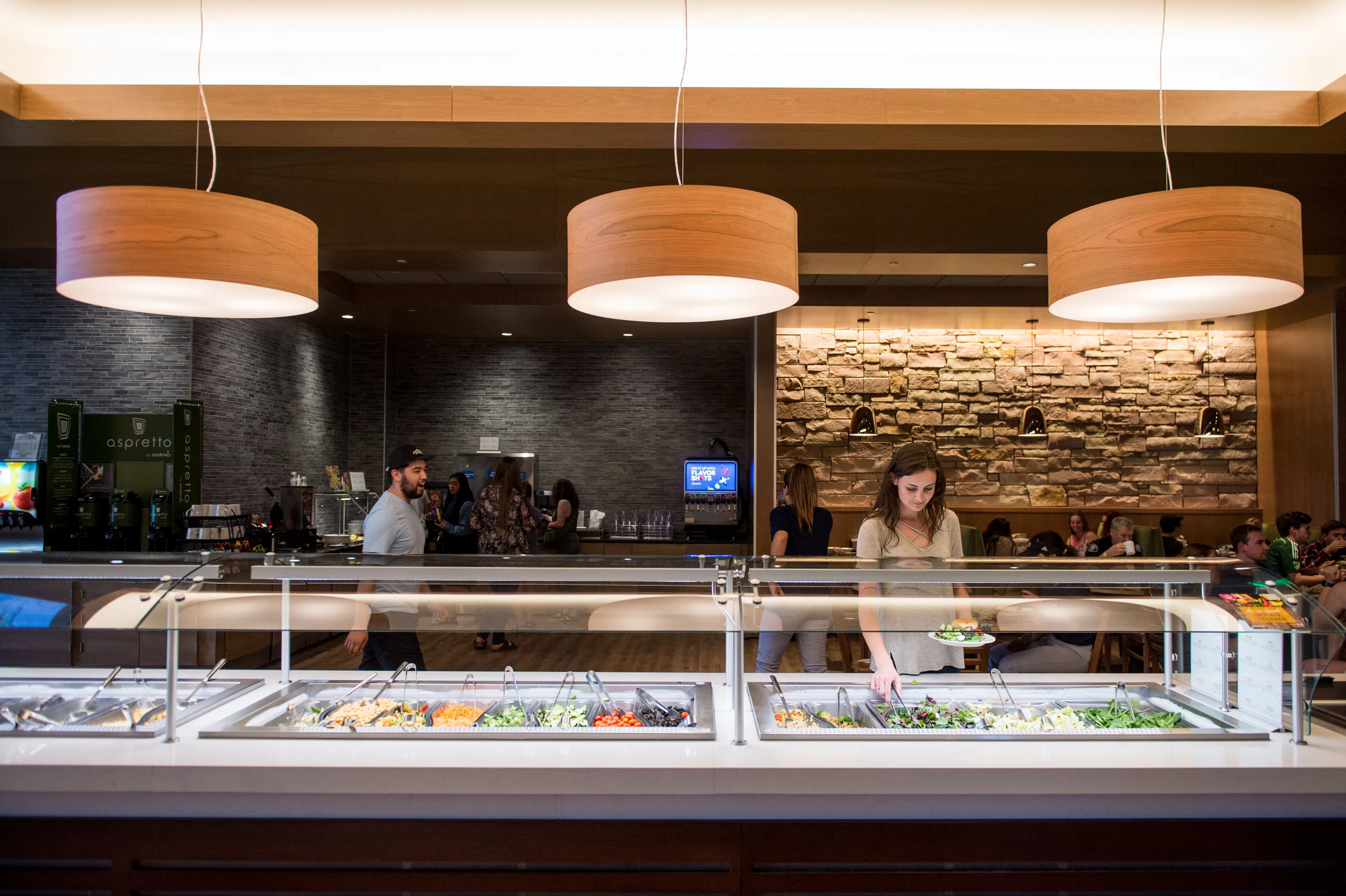 Salad Bar with large lighting above and one girl in line
