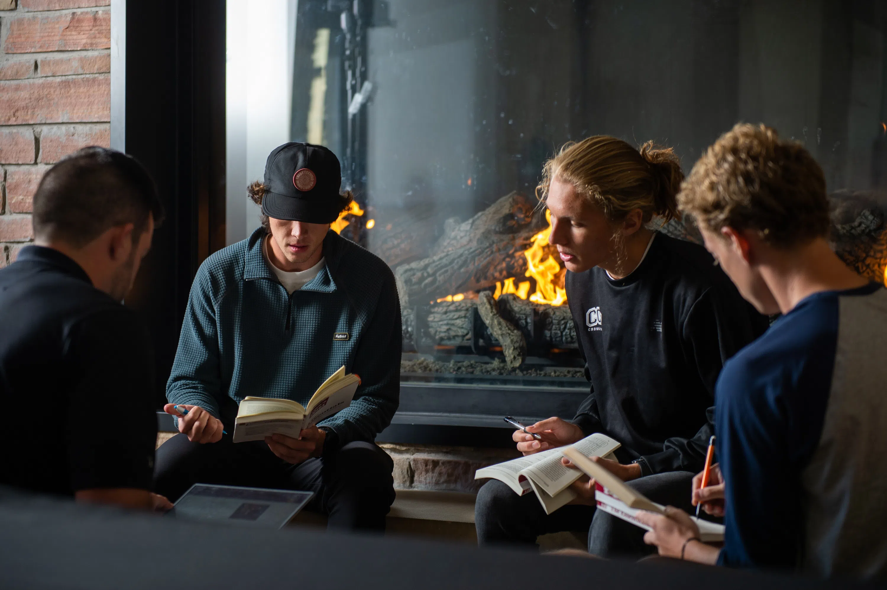 Men sitting in front of a fire reading their Bible and talking