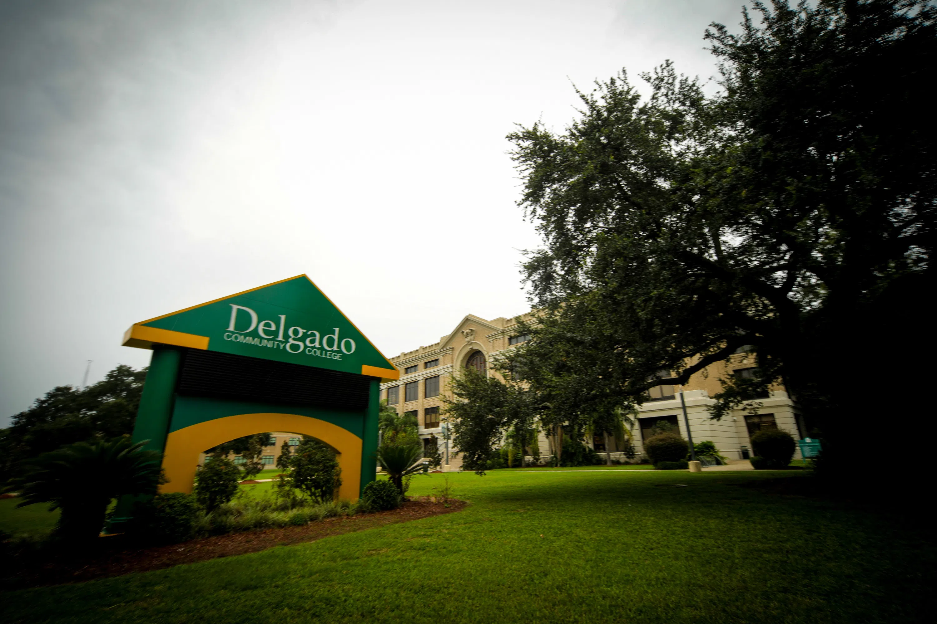 green and gold electronic sign with Delgado logo and building in back