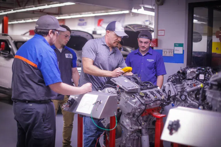 4 people working on car parts