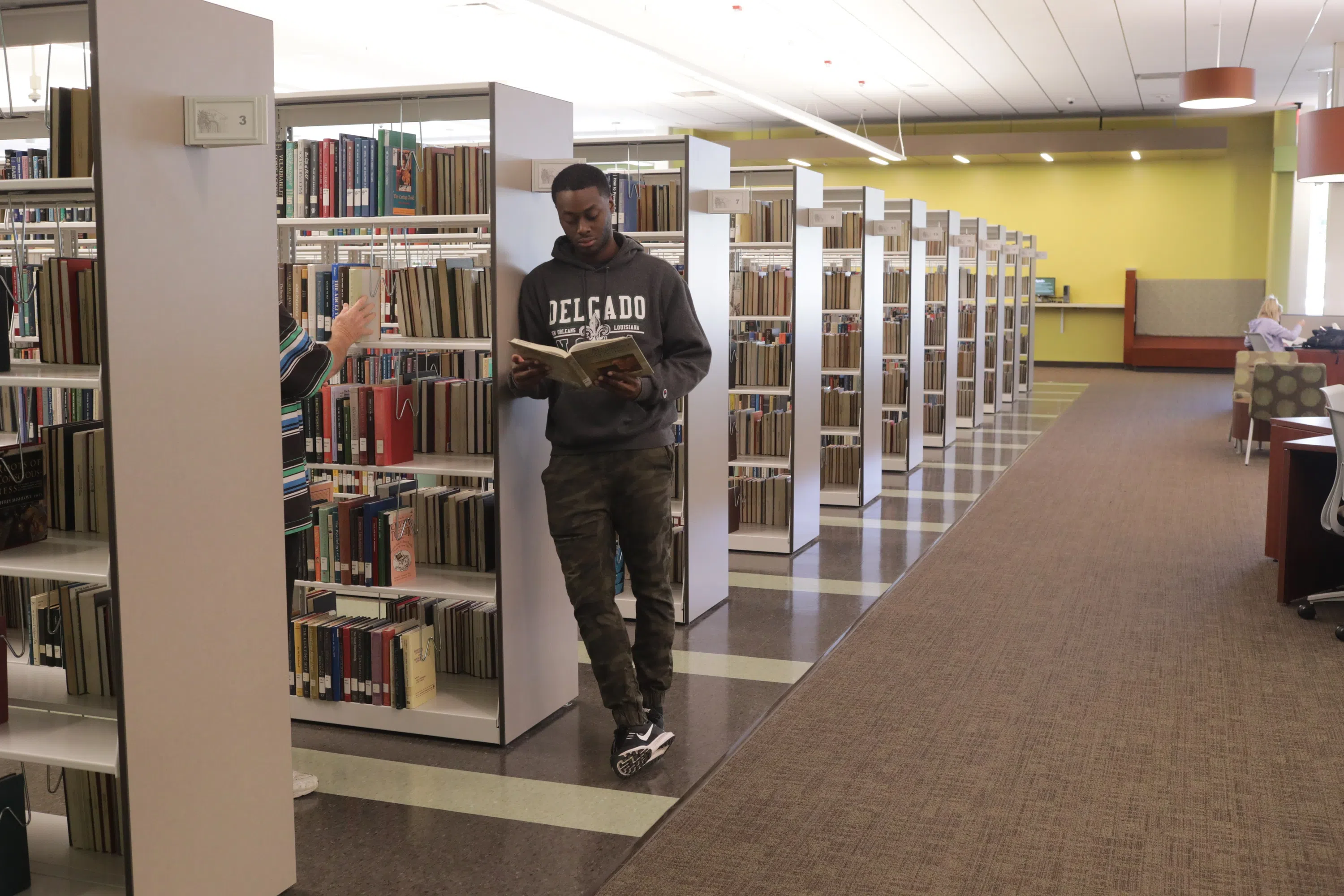 student standing by bookshelves looking at a book